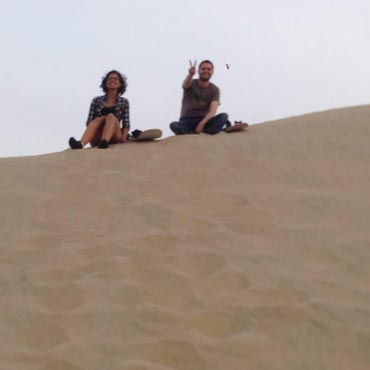 Parm's Yoga | My Journey | Putting Myself Out There in Baby Steps Image of me and a traveller I met while sand-boarding sitting on top of a large sand dune in Huacachina, Peru. Image Credit goes to a fellow traveller in Peru.